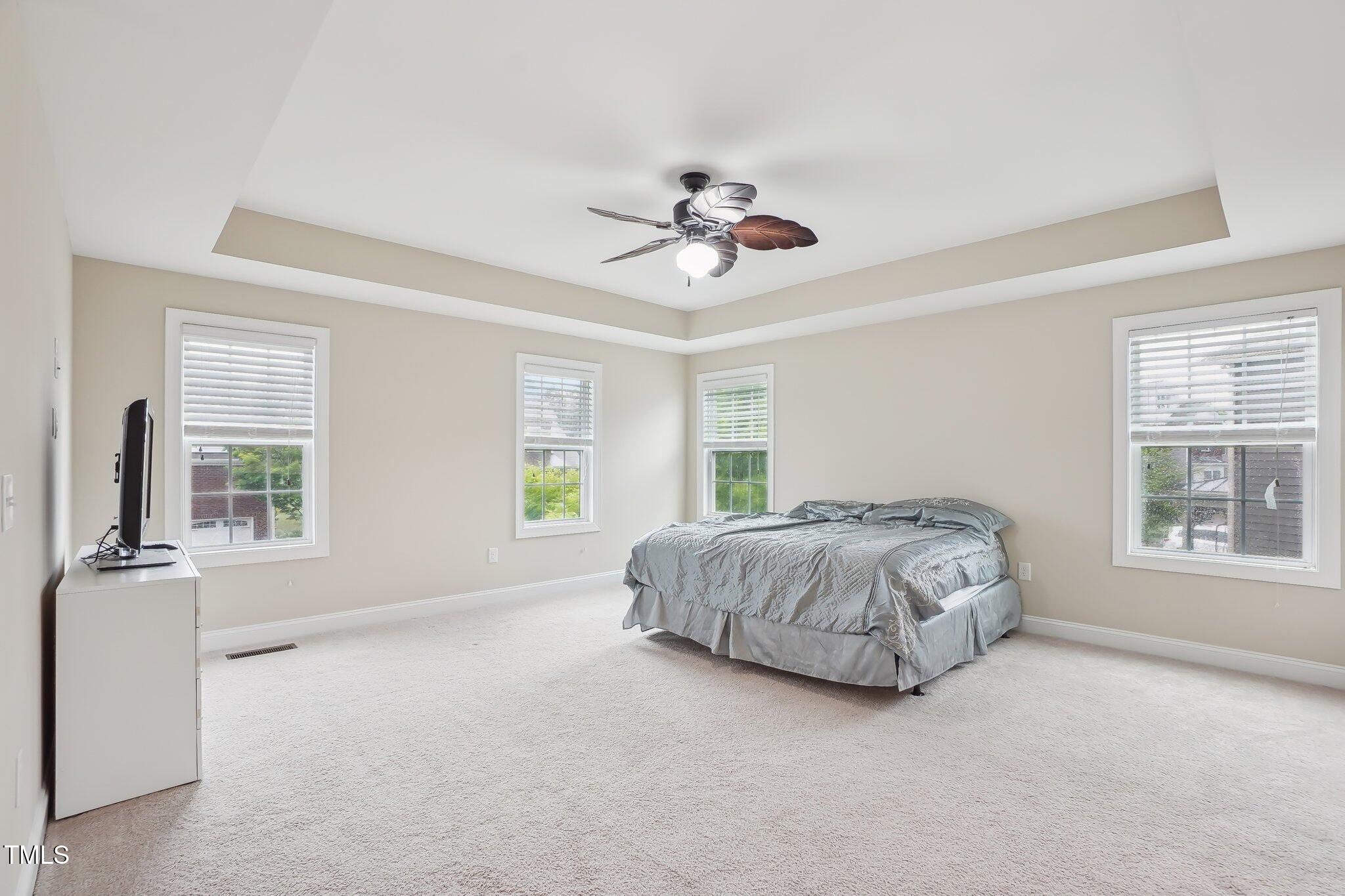 4008 Sykes Street Cary, NC 27519 - Photo 17 of 41 a bed sitting in a spacious bedroom next to a window and a chandelier