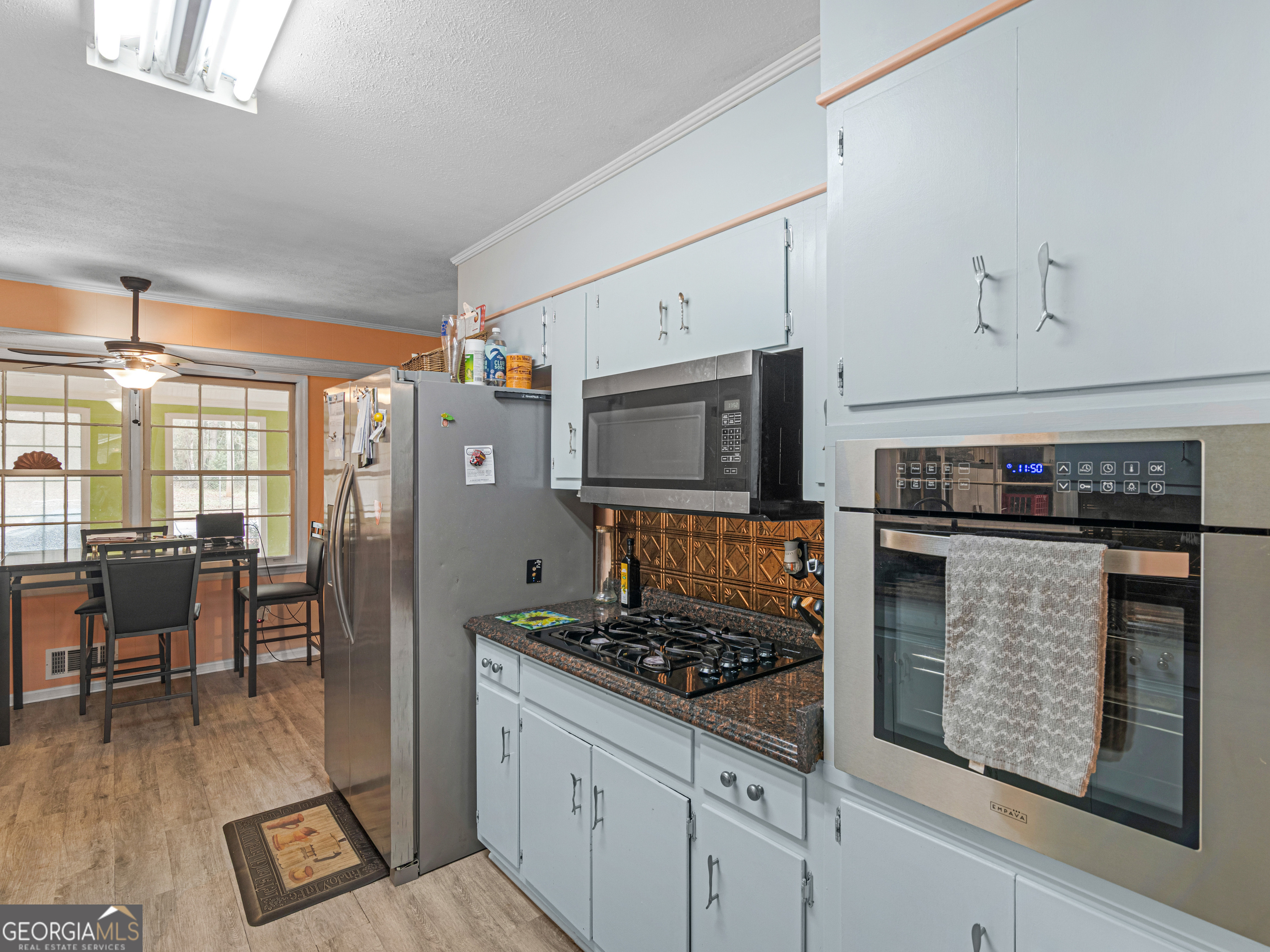 329 Pine Street Barnesville, GA 30204 - Photo 17 of 57 a kitchen with stainless steel appliances granite countertop a stove top oven a sink dishwasher a dining table and chairs with wooden floor
