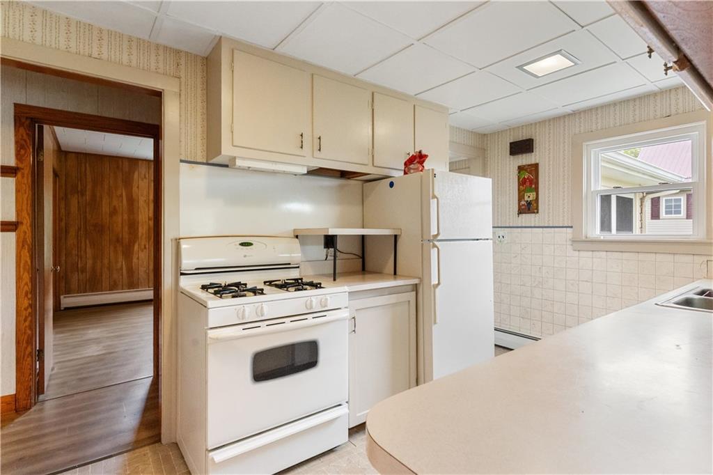 177 Oniontown Road Greenville, PA 16125 - Photo 13 of 18 a kitchen with a white stove and white cabinets with wooden floor