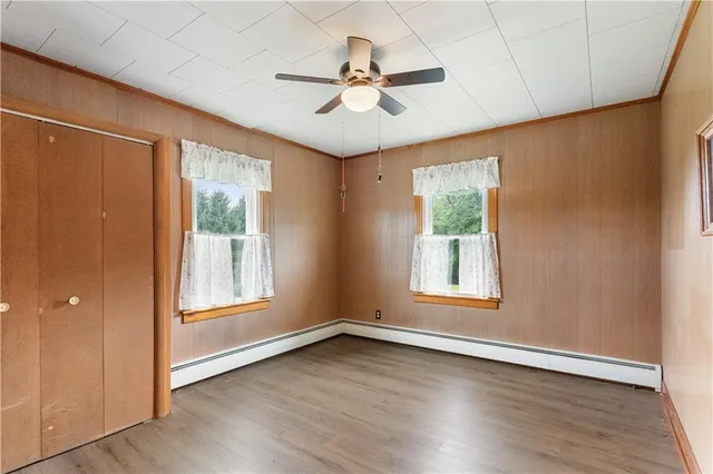 an empty room with wooden floor fan and windows