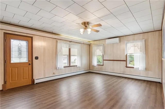 a view of an empty room with a window and wooden floor