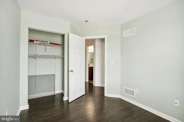 a view of an empty room with wooden floor & closet