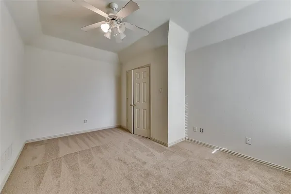 an empty room with a chandelier fan and closet area