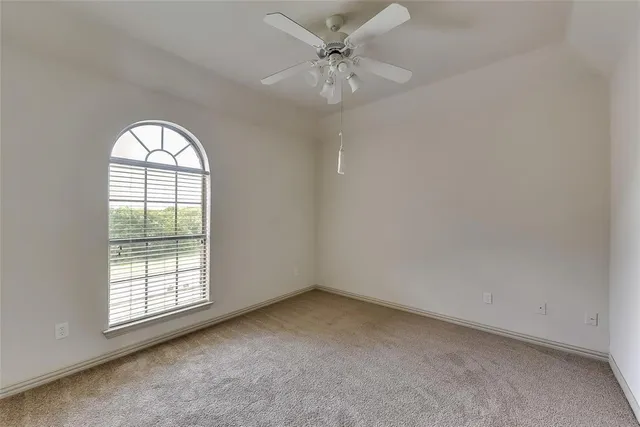 an empty room with windows and ceiling fan