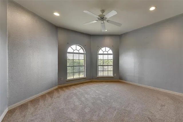 an empty room with windows and ceiling fan