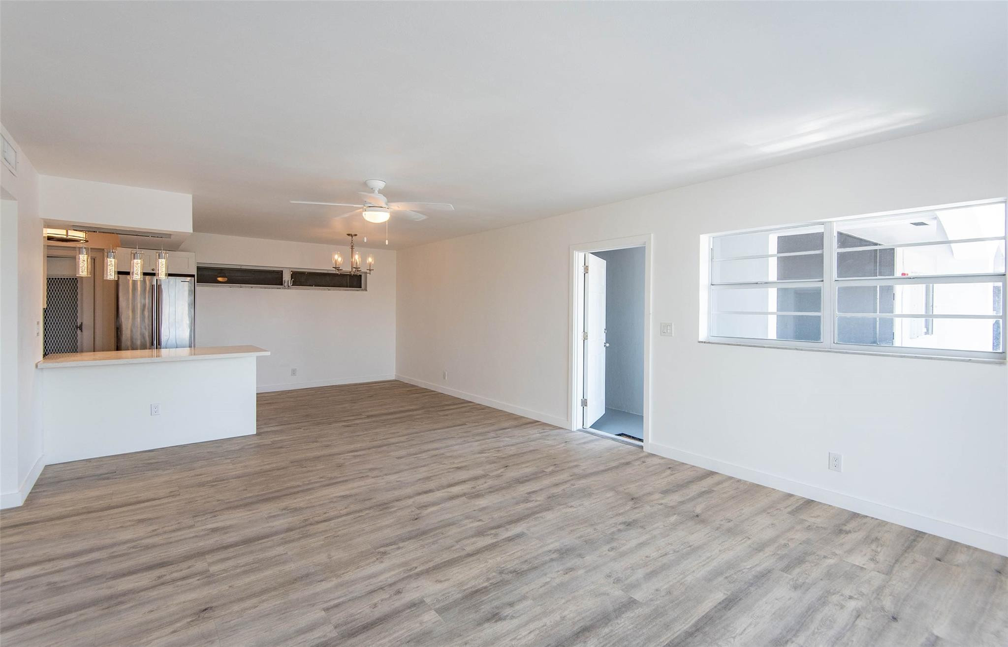 651 Pine Drive, Unit 306 Pompano Beach, FL 33060 - Photo 11 of 36 a view of empty room with wooden floor and kitchen