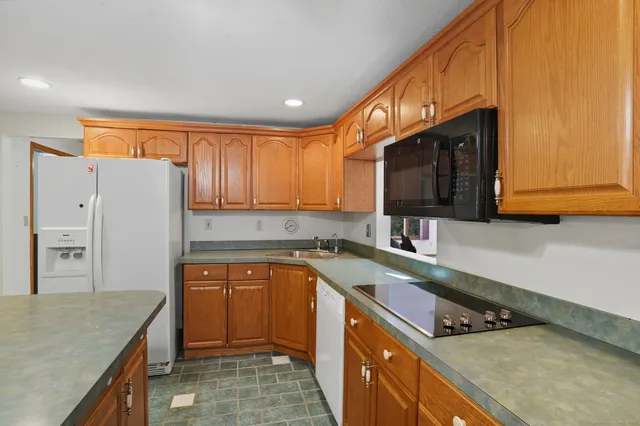 a kitchen with stainless steel appliances granite countertop a sink a stove a refrigerator cabinets and a counter top space