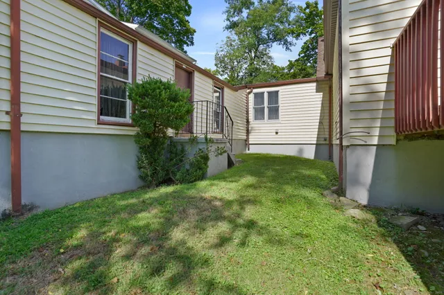 a backyard of a house with plants and large tree