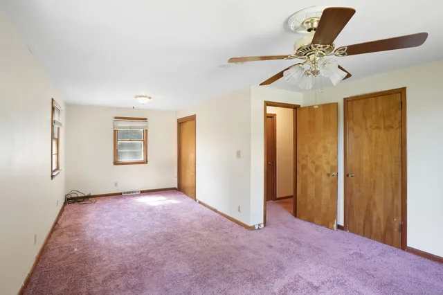 an empty room with closet and fan