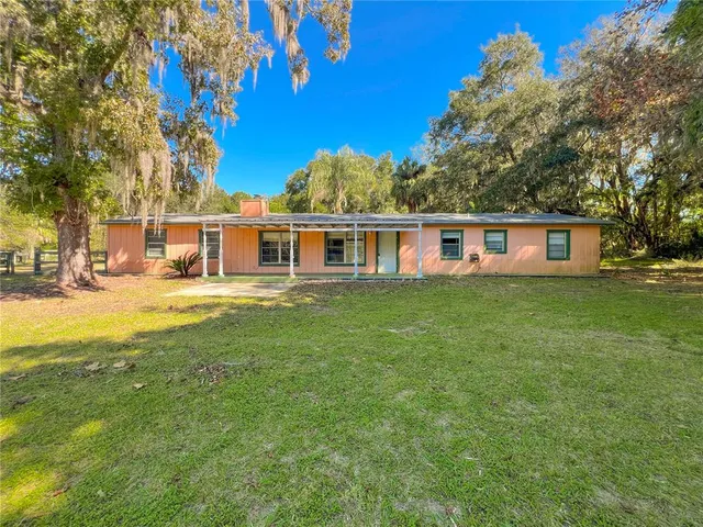 a view of a house with a big yard and large trees