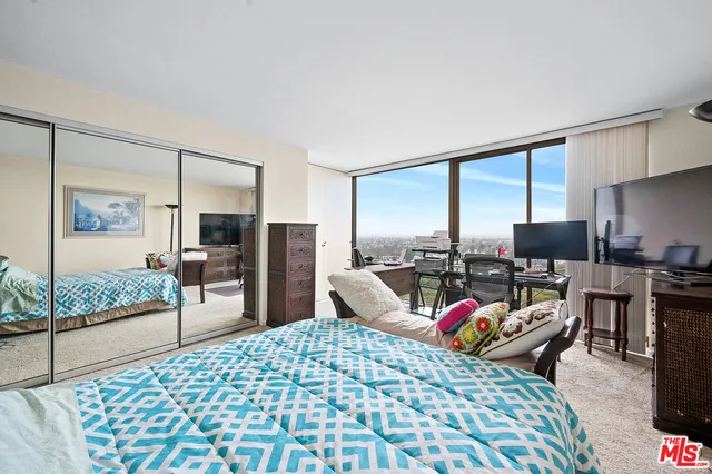 a bedroom with a bed a flat screen tv and a large window