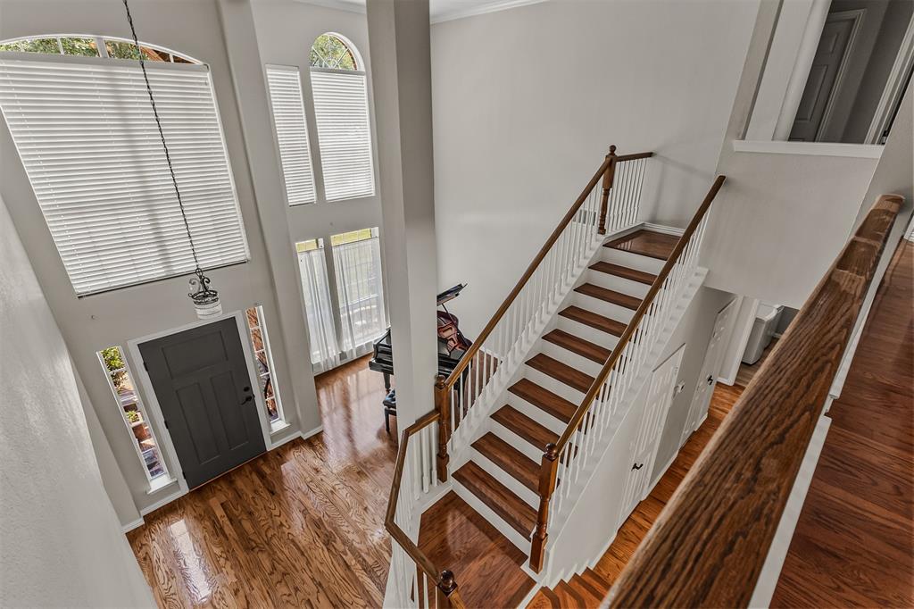 9301 Nottingham Court Rowlett, TX 75088 - Photo 23 of 39 Grand foyer featuring a two-story ceiling, wood-finish flooring, and a prominent staircase with wood railings and white balusters