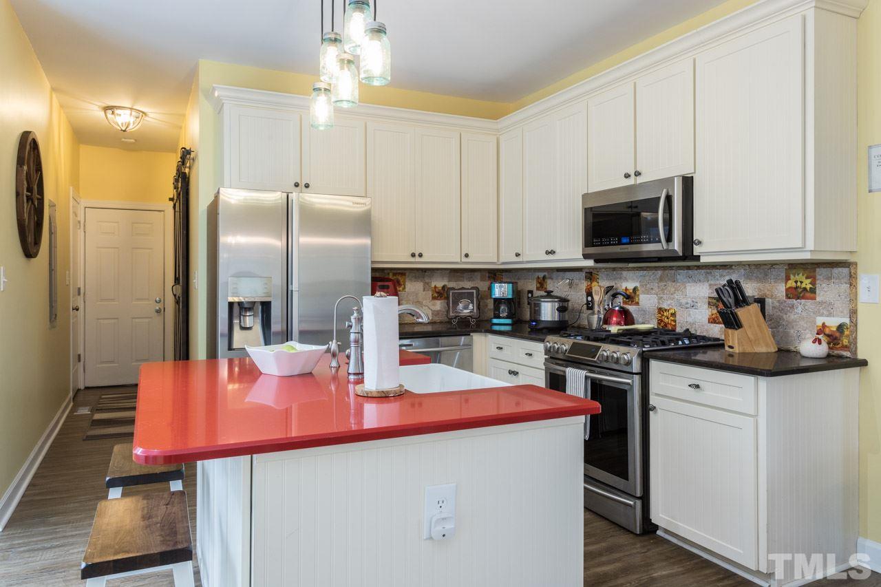 7505 Penny Road Raleigh, NC 27606 - Photo 12 of 25 a kitchen with stainless steel appliances kitchen island granite countertop a refrigerator a stove top oven a sink dishwasher and white cabinets with wooden floor