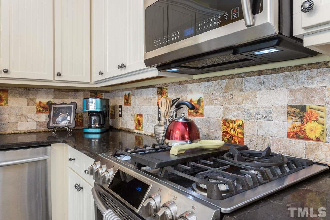 7505 Penny Road Raleigh, NC 27606 - Photo 14 of 25 a kitchen with an oven a stove and white cabinets