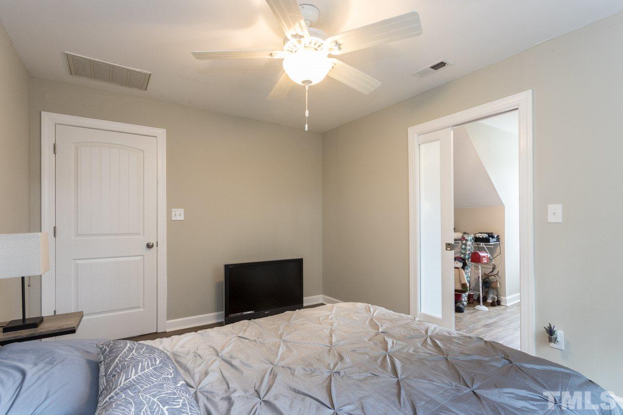7505 Penny Road Raleigh, NC 27606 - Photo 22 of 25 a bedroom with a large bed and a chandelier