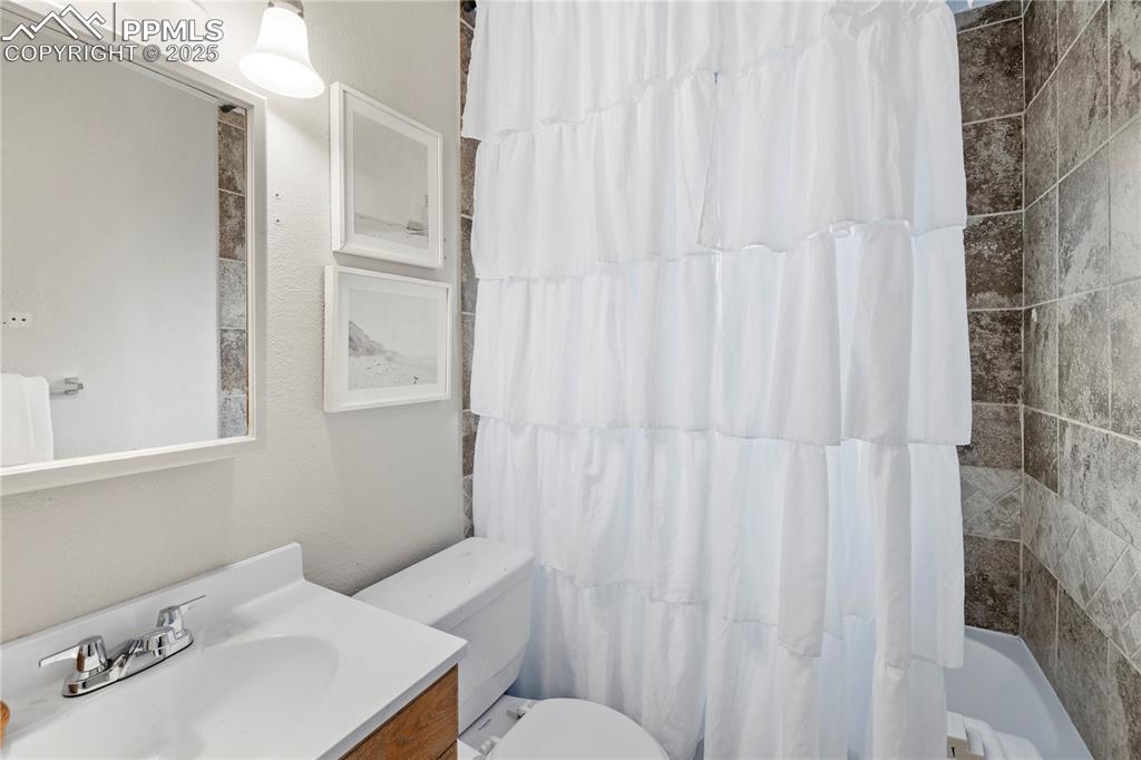 4127 Bent Drive Colorado Springs, CO 80909 - Photo 19 of 41 a bathroom with a sink a toilet and shower curtain