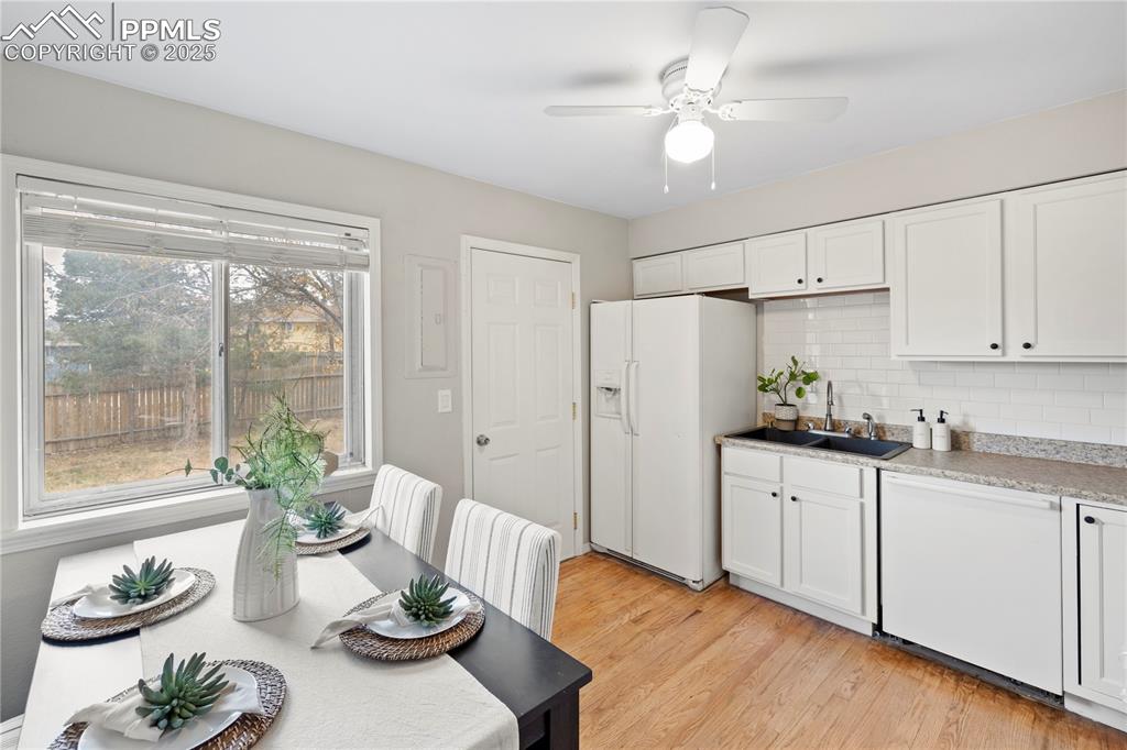 4127 Bent Drive Colorado Springs, CO 80909 - Photo 10 of 41 a kitchen with stainless steel appliances granite countertop a refrigerator a sink and white cabinets with wooden floor