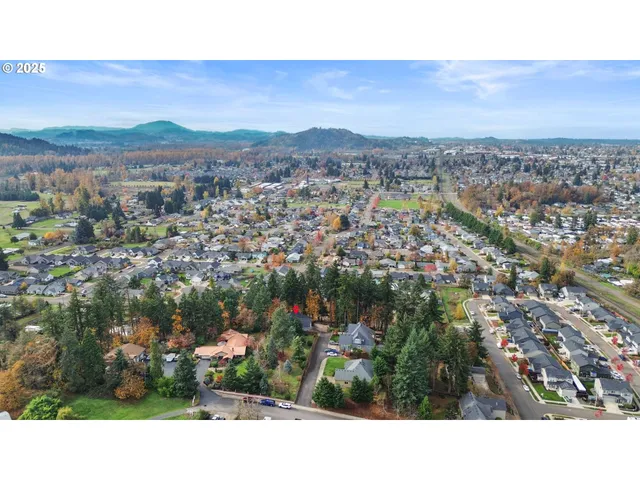a view of house with yard outdoor seating and covered with trees in the background