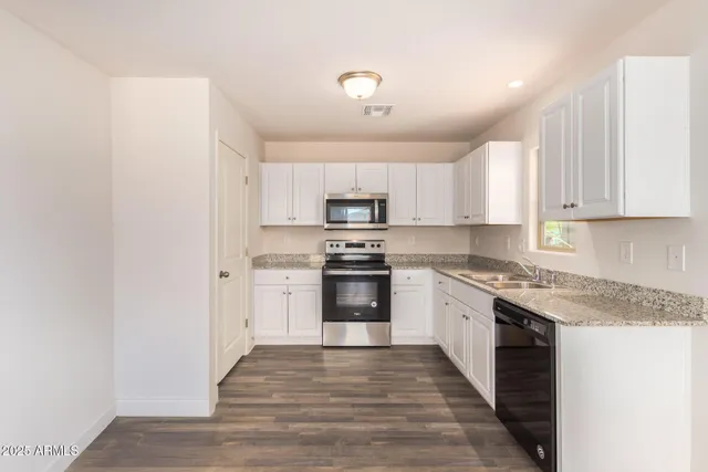 a kitchen with granite countertop a stove top oven and cabinets