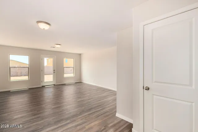 a view of an empty room with window and wooden floor