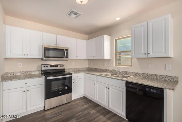 a kitchen with granite countertop white cabinets white stainless steel appliances with a sink and dishwasher