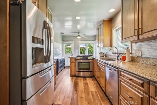 a kitchen with stainless steel appliances granite countertop a table chairs sink refrigerator and cabinets