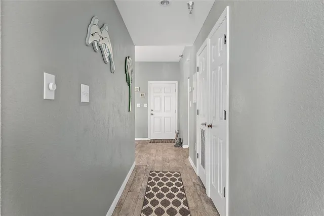 a view of a hallway with wooden floor and a bathroom