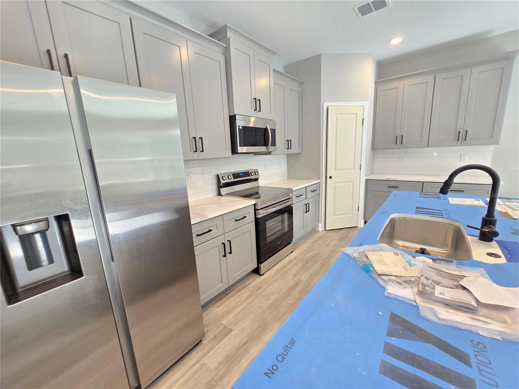 6 Calendula Court Homosassa, FL 34446 - Photo 42 of 67 a kitchen with stainless steel appliances granite countertop a refrigerator a stove a sink and a refrigerator with wooden floor