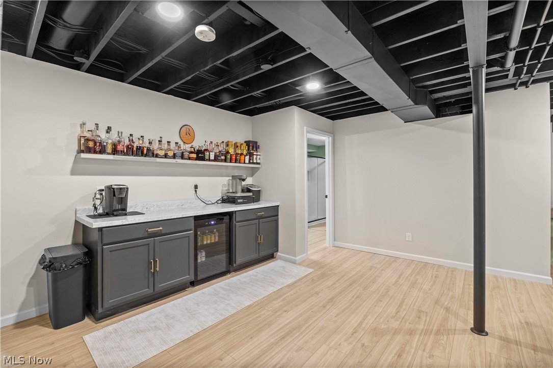 2161 Fowl Road Elyria, OH 44035 - Photo 30 of 46 Spacious rec room featuring light wood-finish flooring, a built-in wet bar with gray cabinetry, a stone-finish countertop, and an integrated beverage cooler