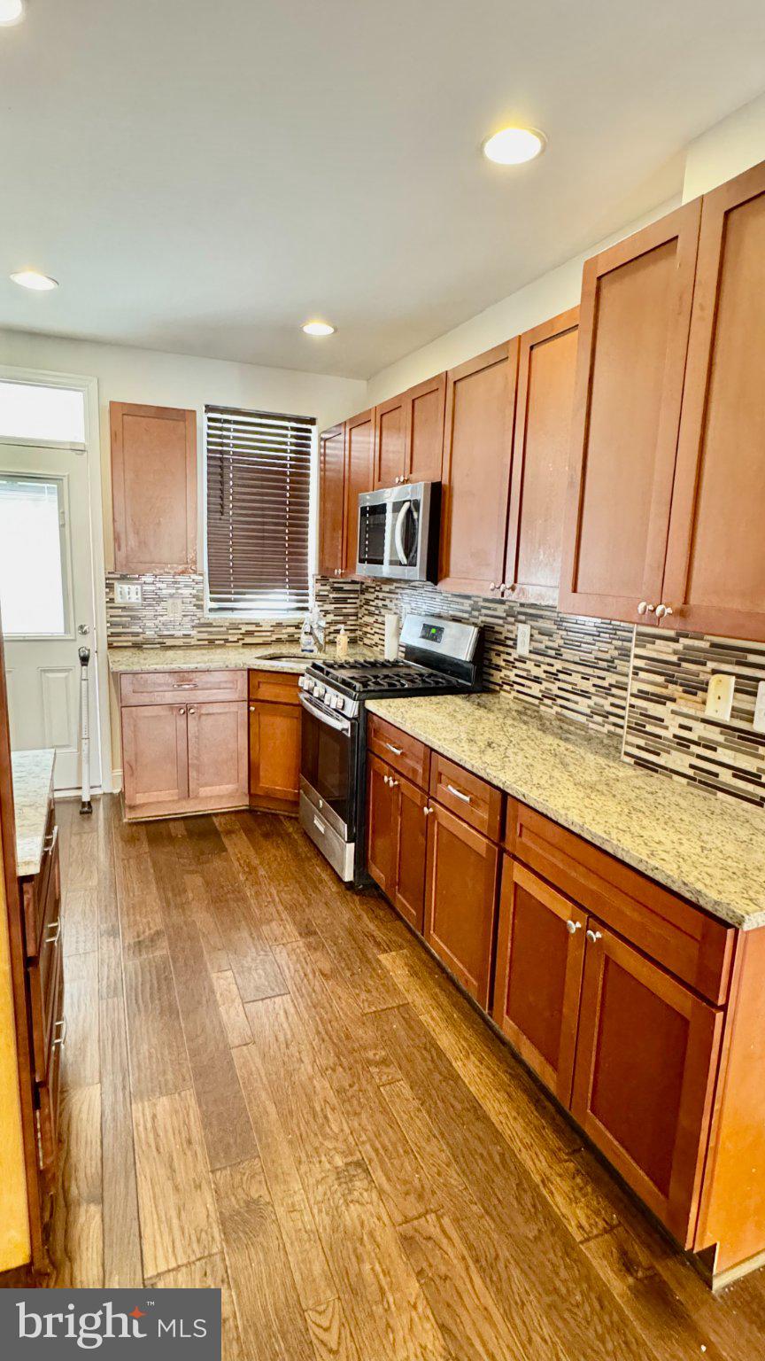 2705 East Biddle Street Baltimore, MD 21213 - Photo 2 of 12 a kitchen with stainless steel appliances granite countertop a stove sink and cabinets