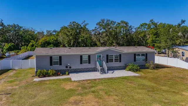 a front view of house with yard and trees in the background