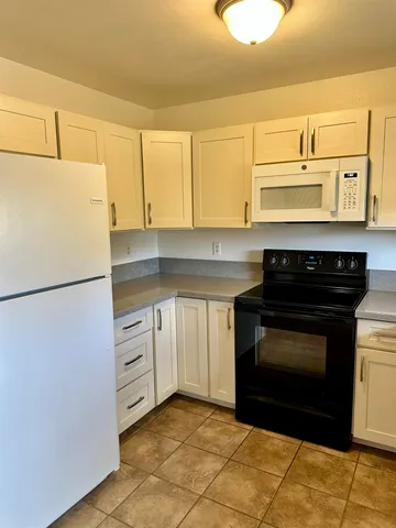 a kitchen with granite countertop white cabinets and black appliances
