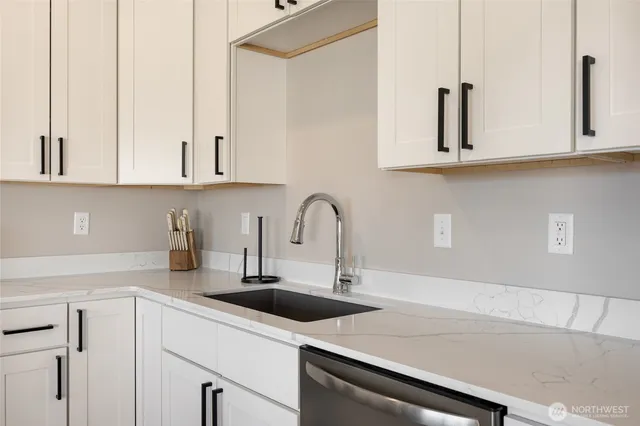 a kitchen with white cabinets a sink and dishwasher