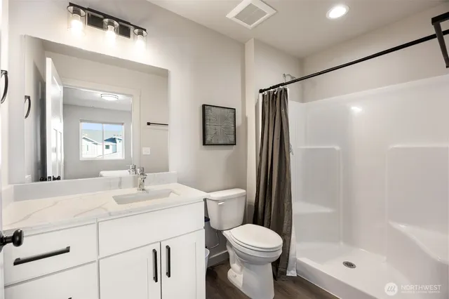 a bathroom with a shower sink vanity mirror and toilet