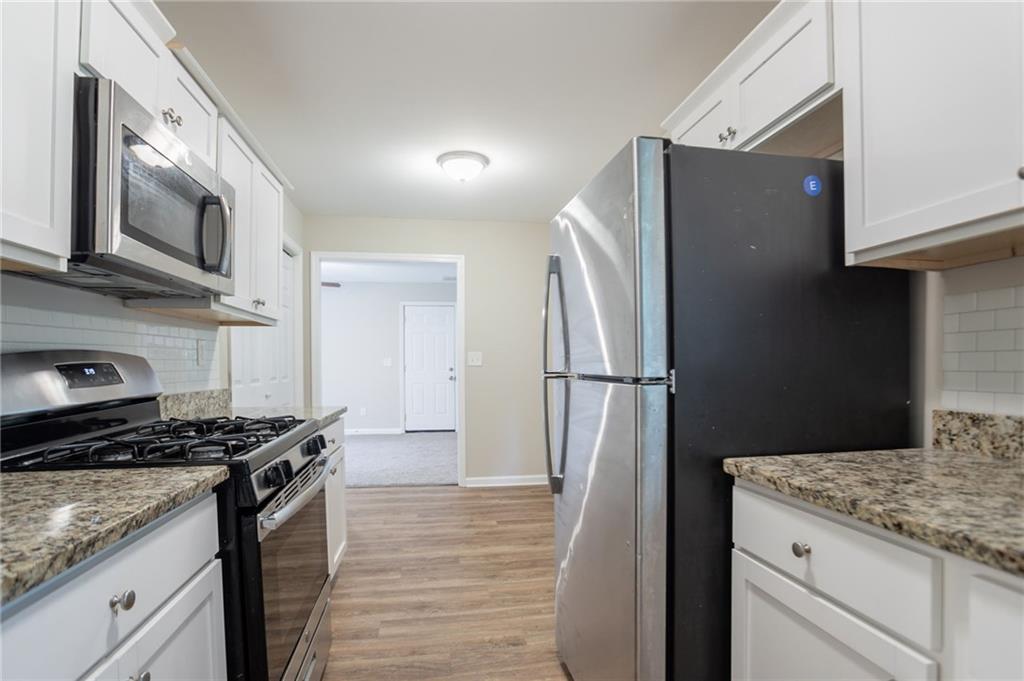 542 Hasty Drive Lithia Springs, GA 30122 - Photo 12 of 44 a kitchen with granite countertop a refrigerator and a stove top oven