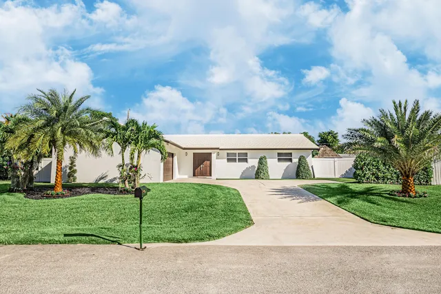 a view of house in front of a big yard with potted plants