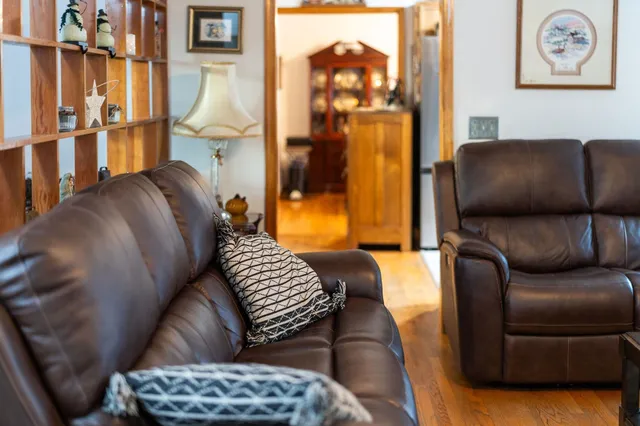 a living room with furniture a air conditioner vent and white walls
