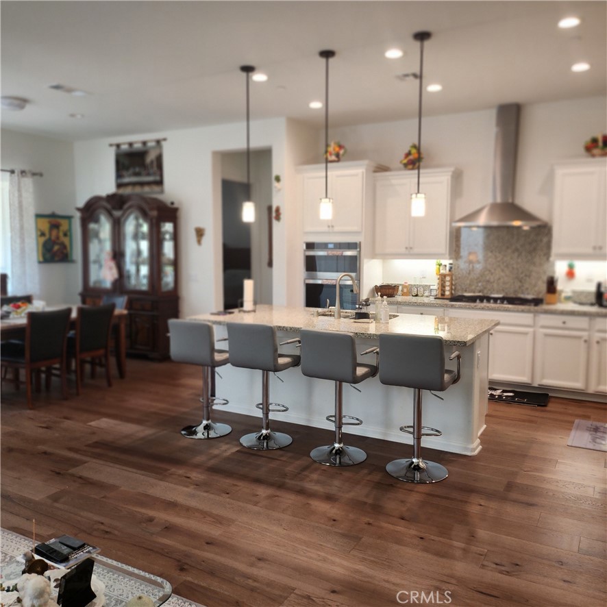 11882 Wandering Way Corona, CA 92883 - Photo 4 of 38 a kitchen with stainless steel appliances kitchen island granite countertop a table chairs sink and cabinets