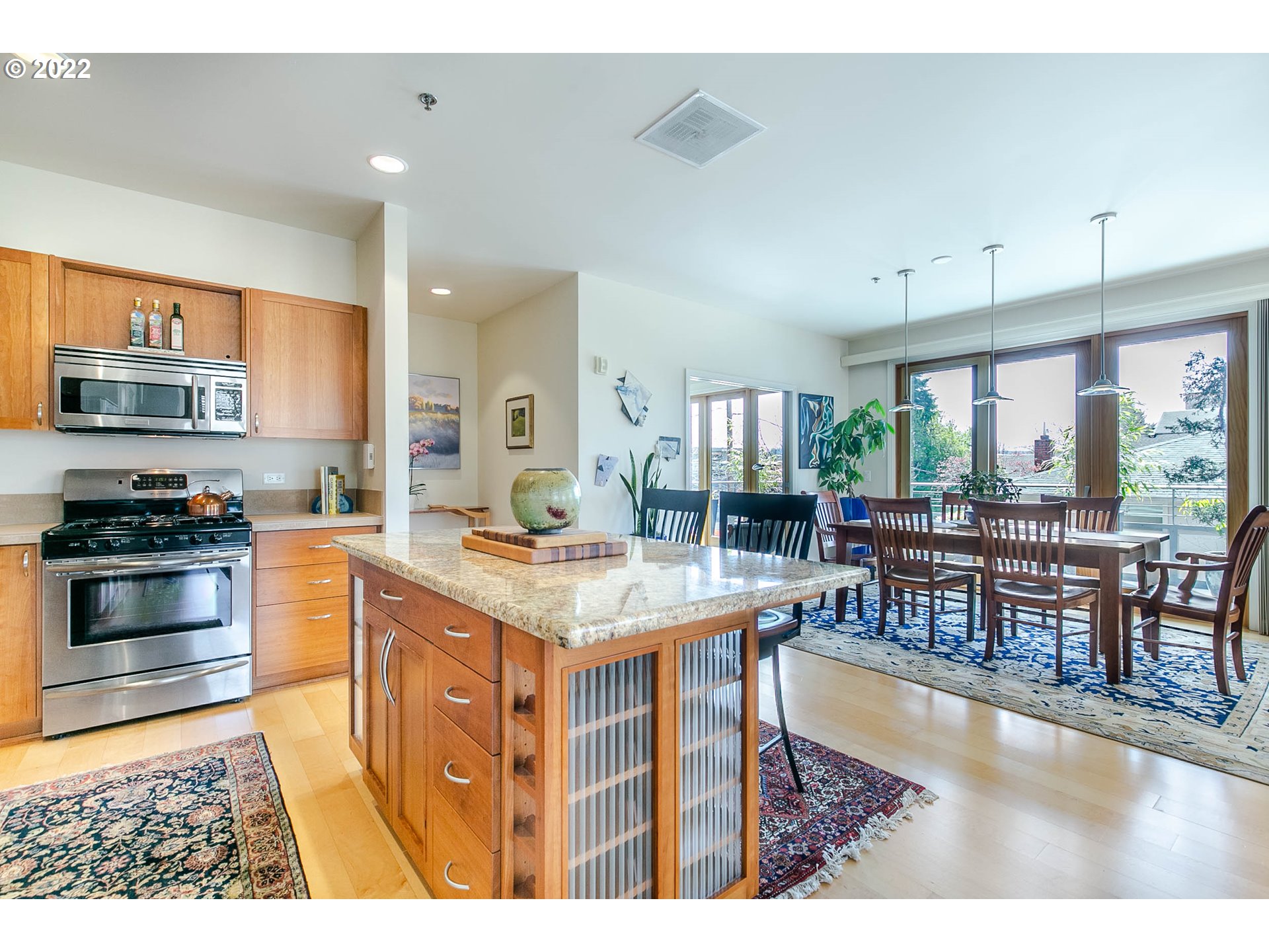1375 Olive Street, Unit 201 Eugene, OR 97401 - Photo 10 of 32 a kitchen with stainless steel appliances kitchen island granite countertop a stove top oven a sink a dining table and chairs with wooden floor