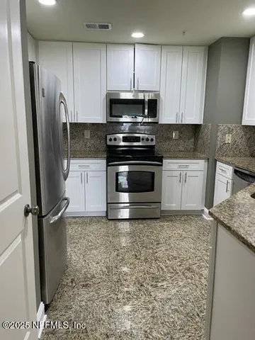 a kitchen with granite countertop a stove a sink and a microwave