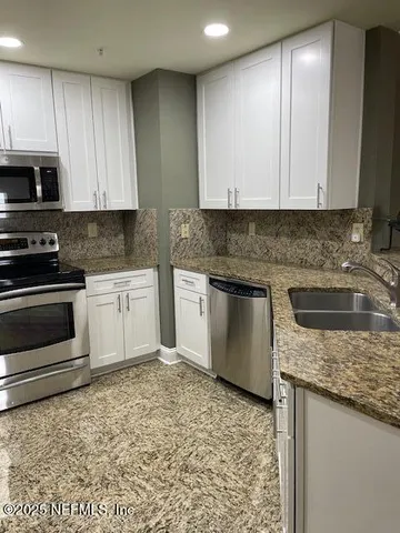 a kitchen with stainless steel appliances granite countertop a refrigerator a sink a stove a microwave and island