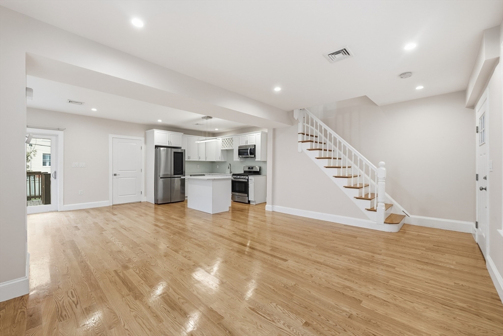 31 Chipman Street Boston, MA 02124 - Photo 5 of 37 a view of an empty room with wooden floor and stairs