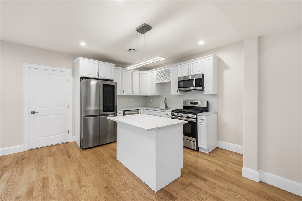31 Chipman Street Boston, MA 02124 - Photo 6 of 37 a kitchen with a refrigerator a stove top oven and wooden floor