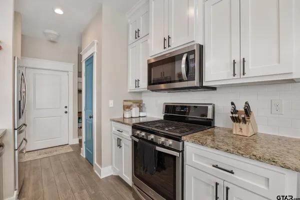 a kitchen with white cabinets and stainless steel appliances