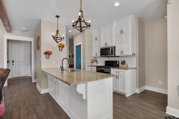 a kitchen with granite countertop a sink a stove top oven a counter space and cabinets