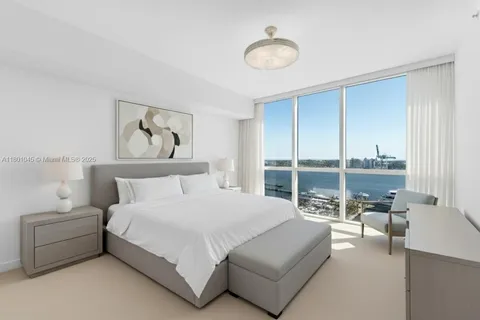 a spacious bedroom with a bed and glass window