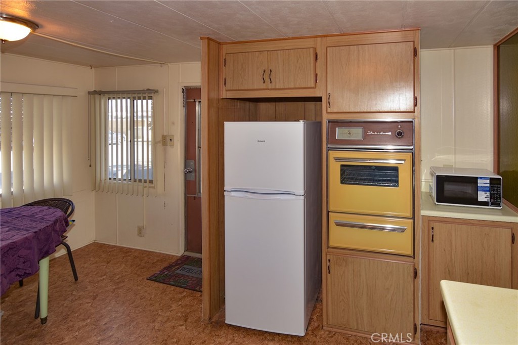 23456 Ottawa Road, Unit 4 Apple Valley, CA 92308 - Photo 5 of 17 a white refrigerator freezer and a stove sitting inside of a kitchen