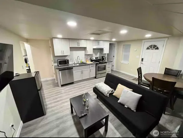 a living room with furniture kitchen view and a wooden floor