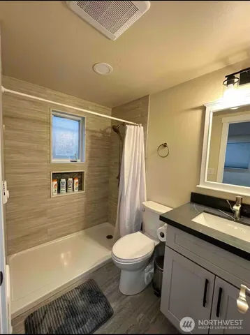 a bathroom with a granite countertop bathtub sink vanity mirror and toilet