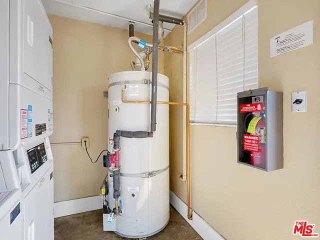 a utility room with fridge and wooden floor